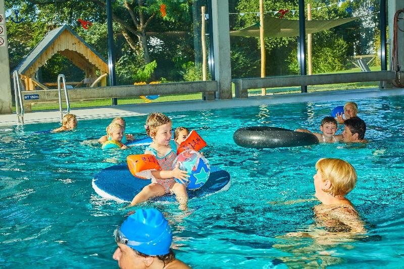 Hallenbad Hier sieht man das Schwimmbecken mit verschiedenen Personen im Wasser