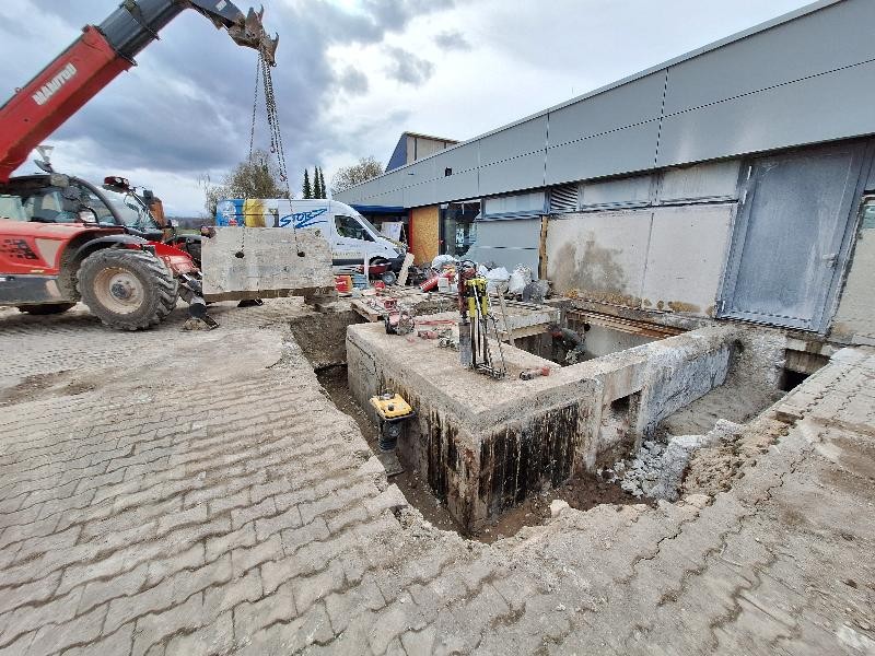 Hier sieht man einen Bagger der ein Betonteil weghebt
