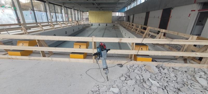 Hier sieht man das leere Becken mit einer Absturtzsicherung und der fehlenden Deckenverkleidung mit einem Presslufthammer und kaputte Fliesen