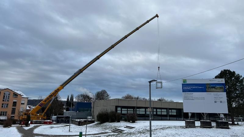 Kran mit Container Hier sieht man einen Kran der einen Container über das Gebäude hebt.