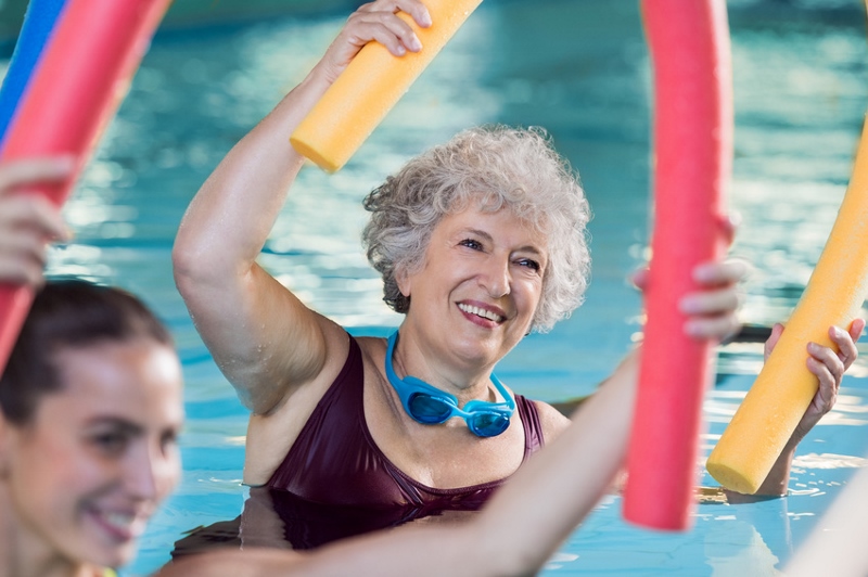 Hier sieht man Personen die mit einer Poolnudel Wassergymnastik machen